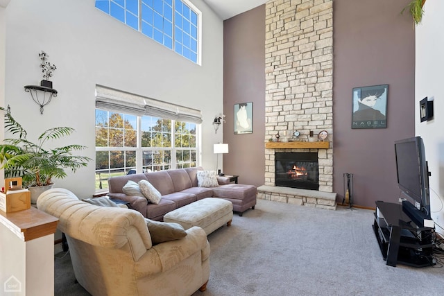 living room with a stone fireplace, carpet flooring, and a towering ceiling