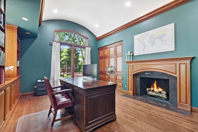 office with vaulted ceiling, light wood-type flooring, and a fireplace