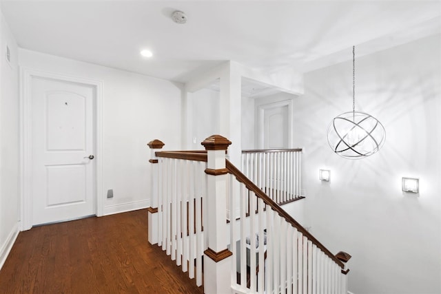 hallway featuring dark wood-type flooring and an inviting chandelier