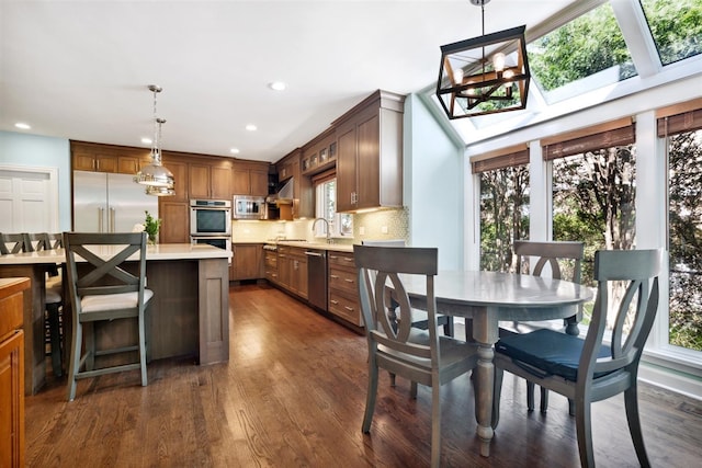 kitchen featuring a skylight, decorative light fixtures, built in appliances, and plenty of natural light