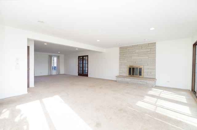 unfurnished living room with light carpet and a fireplace