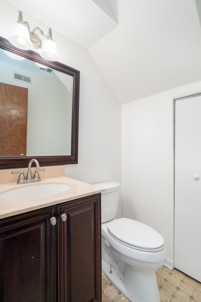 bathroom with vanity, toilet, and lofted ceiling