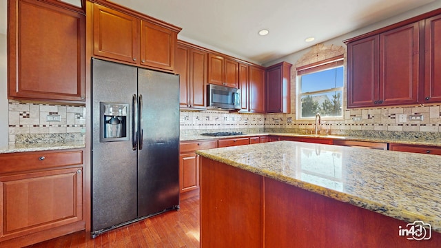 kitchen featuring stainless steel appliances, sink, light wood-type flooring, light stone counters, and tasteful backsplash