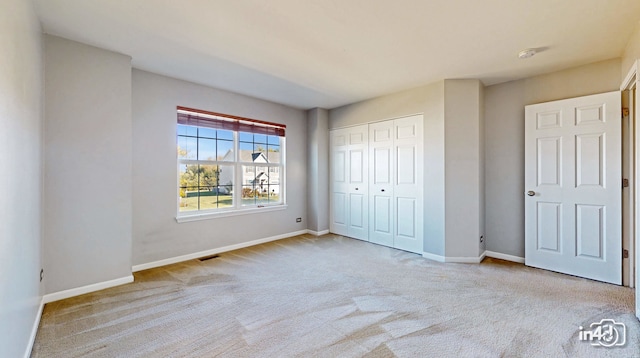 unfurnished bedroom with a closet and light colored carpet