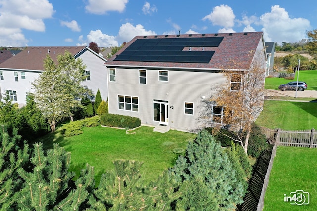 back of property with a lawn and solar panels