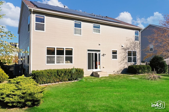 back of house with a lawn and solar panels