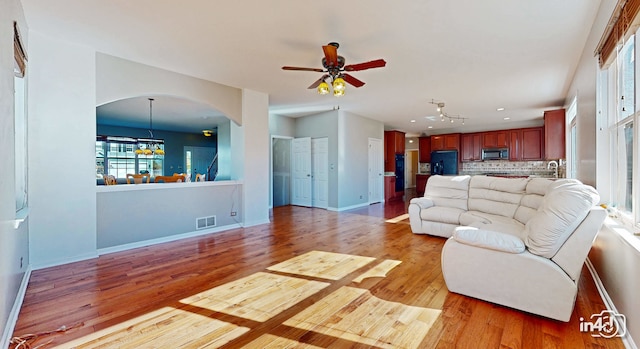 living room featuring sink, light wood-type flooring, and ceiling fan with notable chandelier