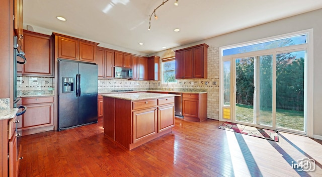 kitchen featuring light stone counters, stainless steel appliances, dark hardwood / wood-style flooring, and a center island