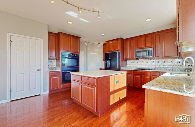 kitchen featuring backsplash, sink, black appliances, a center island, and dark hardwood / wood-style flooring