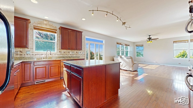 kitchen with a kitchen island, decorative backsplash, hardwood / wood-style flooring, sink, and refrigerator