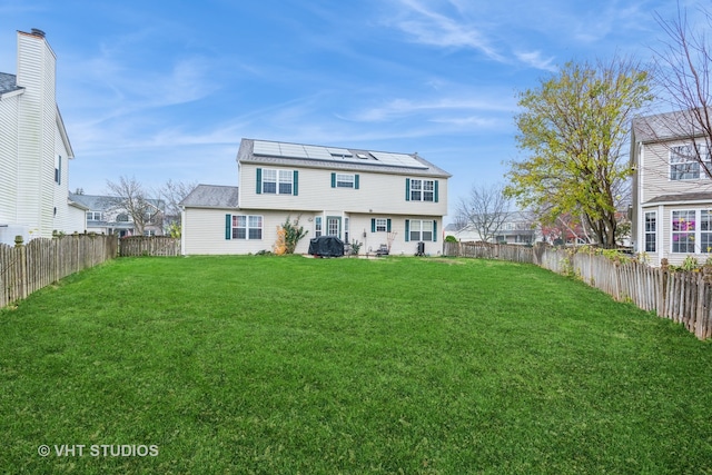 back of property featuring solar panels and a lawn