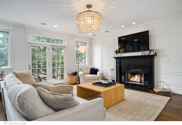 living room with hardwood / wood-style flooring, a healthy amount of sunlight, ornamental molding, and a chandelier