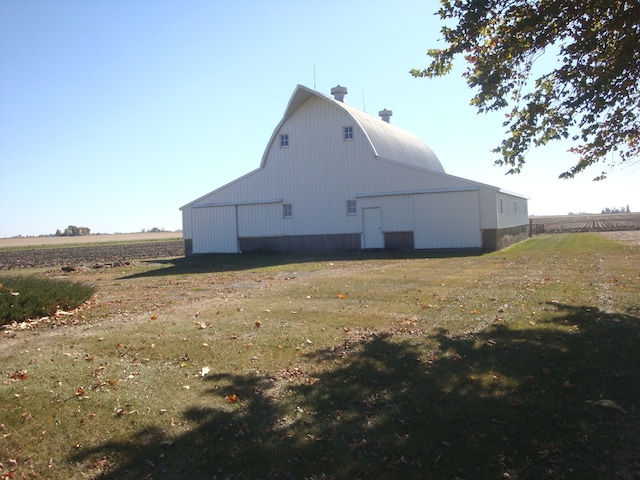 view of home's exterior featuring a lawn, a rural view, and an outdoor structure