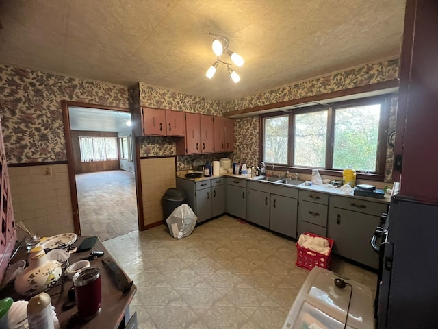 kitchen featuring a textured ceiling, gray cabinets, tile walls, and a healthy amount of sunlight