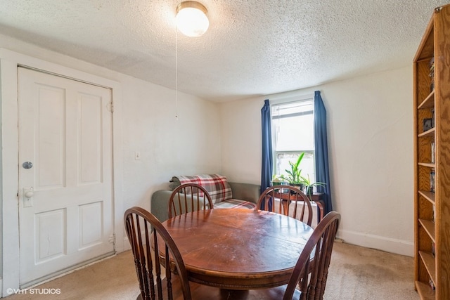 carpeted dining room featuring a textured ceiling