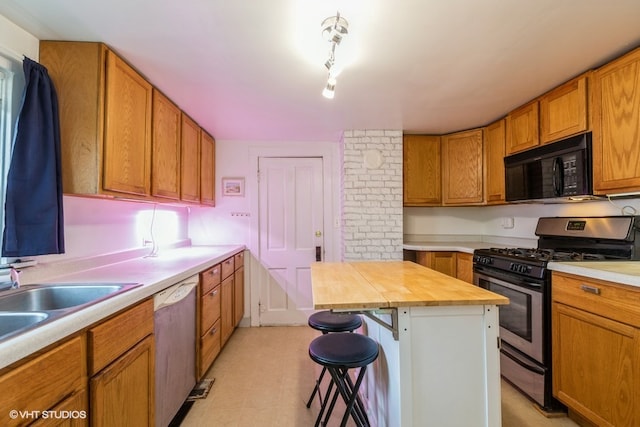 kitchen featuring butcher block counters, a center island, a breakfast bar area, sink, and appliances with stainless steel finishes