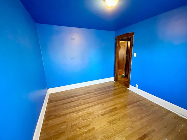 spare room with baseboards and wood finished floors