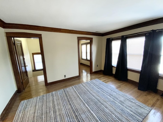 spare room with ornamental molding, baseboards, and wood finished floors