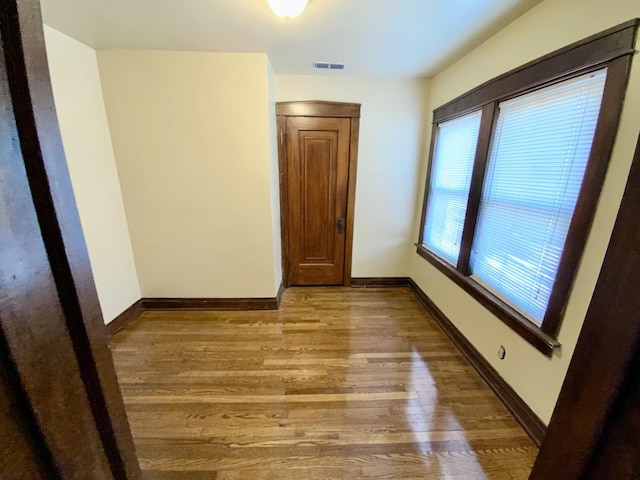 empty room featuring light wood-type flooring, visible vents, and baseboards