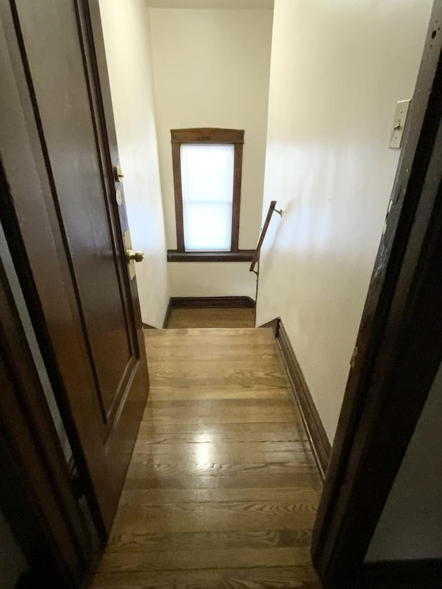 corridor with light wood-type flooring, baseboards, and an upstairs landing