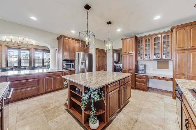 kitchen featuring ornate columns, stainless steel appliances, light stone counters, a center island, and pendant lighting