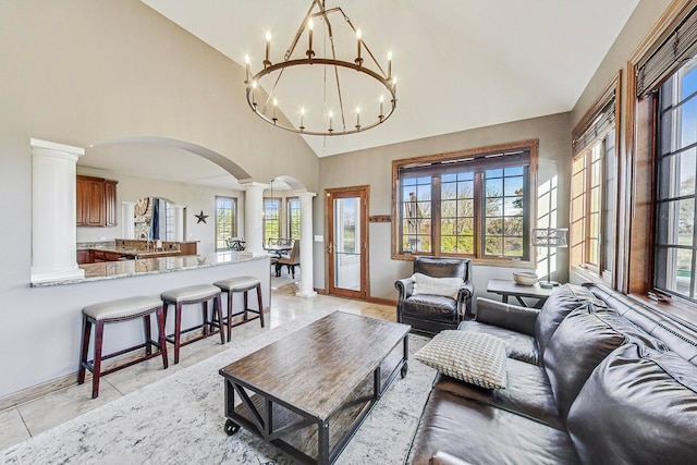 living room featuring sink, high vaulted ceiling, and decorative columns