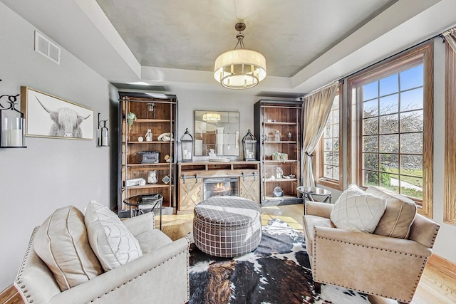 living area with light hardwood / wood-style floors and a tray ceiling