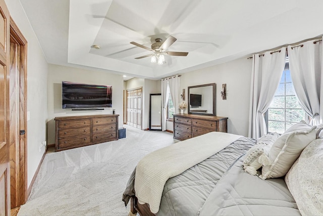 bedroom featuring light colored carpet, ceiling fan, and a raised ceiling