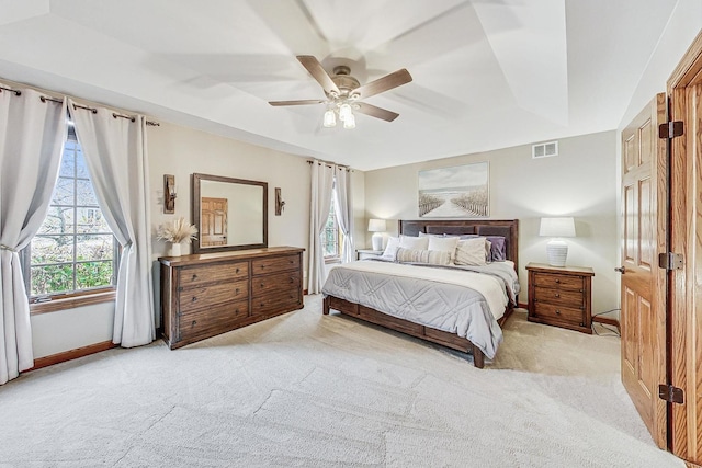 carpeted bedroom with ceiling fan and a raised ceiling