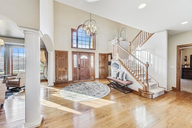 foyer featuring an inviting chandelier, ornate columns, and light wood-type flooring