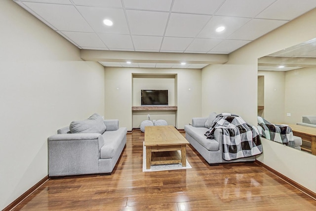 living room featuring a drop ceiling and wood-type flooring