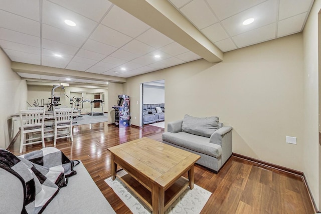 living room featuring a paneled ceiling and dark hardwood / wood-style floors