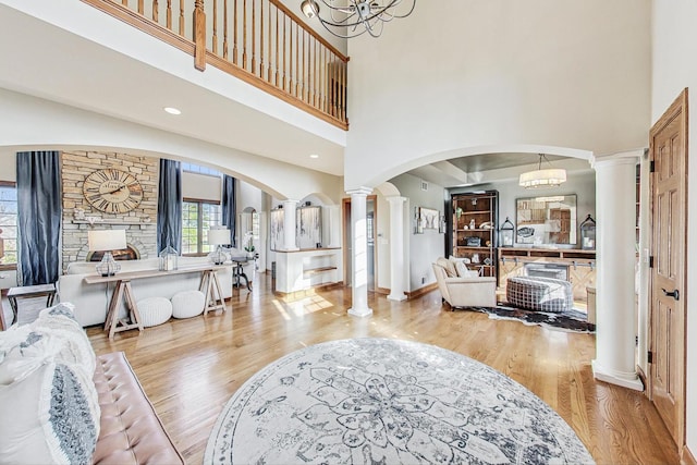 entrance foyer with light hardwood / wood-style flooring, a chandelier, ornate columns, and a towering ceiling