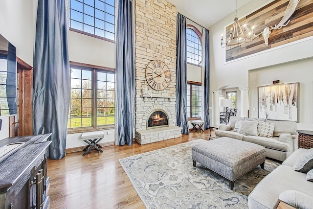 living room with light hardwood / wood-style flooring, a fireplace, a high ceiling, and plenty of natural light