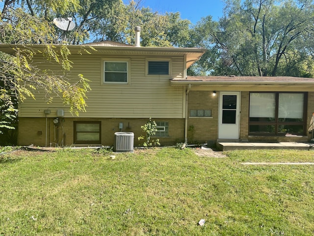 rear view of house featuring cooling unit and a lawn