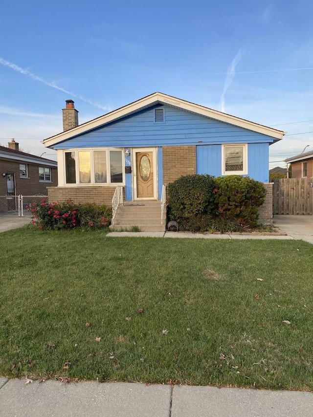 bungalow-style home featuring fence, a chimney, a front lawn, and brick siding
