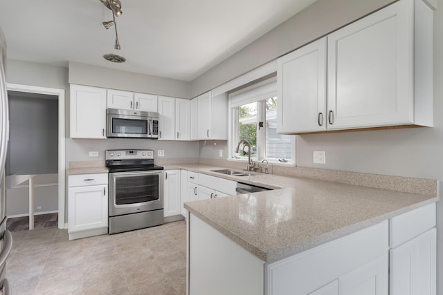 kitchen with kitchen peninsula, rail lighting, white cabinetry, sink, and stainless steel appliances