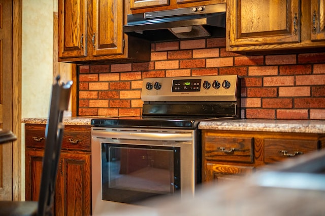 4140 E German Valley Rd, Freeport, IL 61032 - kitchen with stainless steel electric range, under cabinet range hood, decorative backsplash, and brown cabinets
