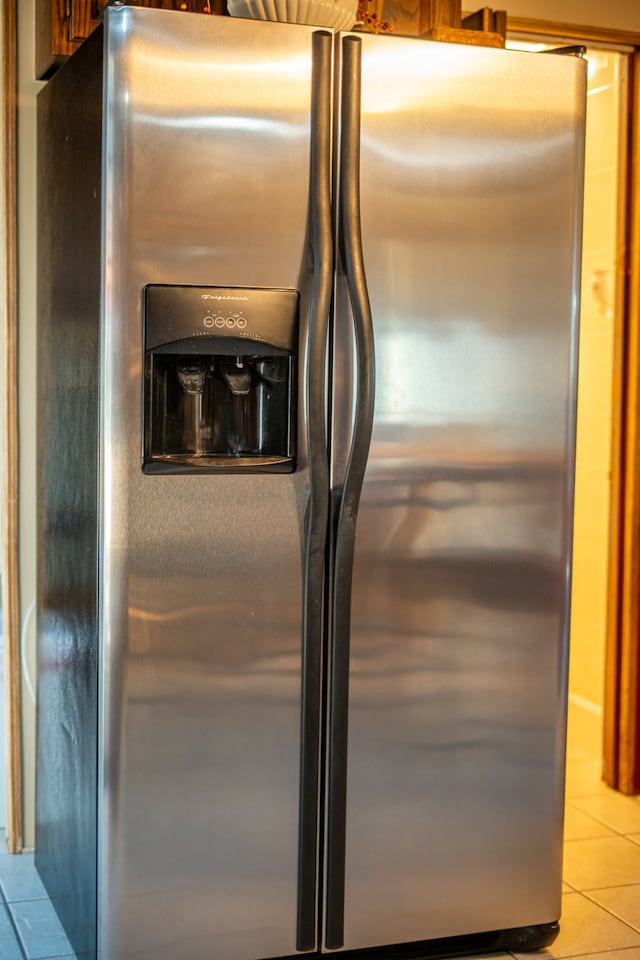 room details featuring stainless steel refrigerator with ice dispenser and light tile patterned floors