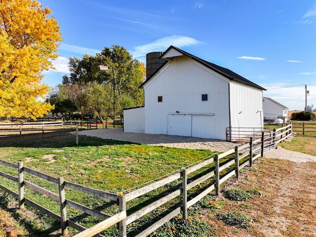 view of home's exterior with a rural view and an outbuilding