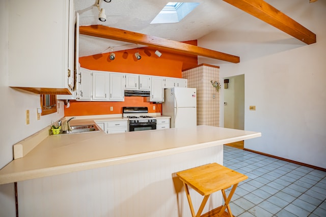 kitchen featuring kitchen peninsula, lofted ceiling with skylight, white refrigerator, black gas stove, and white cabinetry