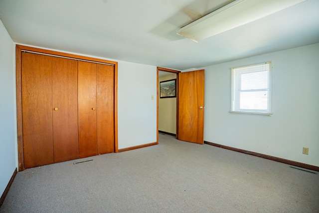 unfurnished bedroom featuring a closet and light colored carpet