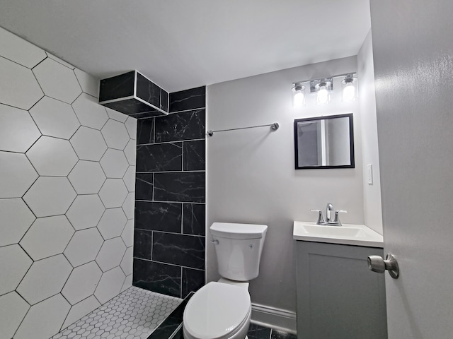 bathroom with vanity, toilet, tile patterned floors, and tiled shower