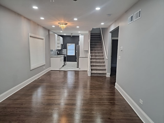 unfurnished living room featuring dark wood-type flooring, sink, and a chandelier