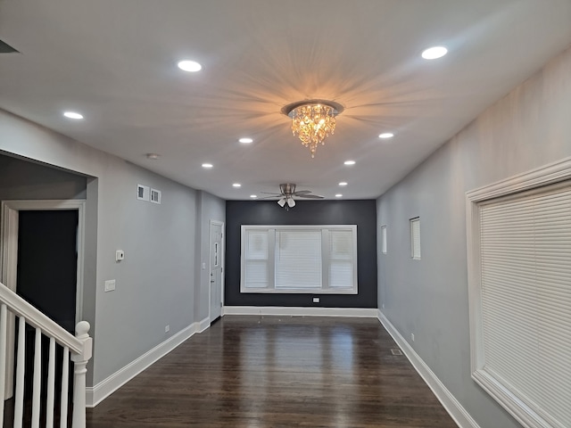 spare room featuring dark hardwood / wood-style floors and ceiling fan with notable chandelier