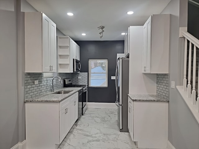 kitchen with sink, light stone countertops, white cabinets, appliances with stainless steel finishes, and tasteful backsplash