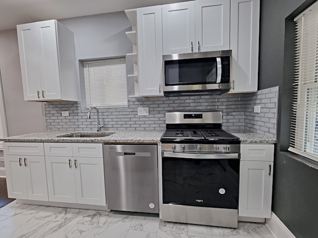 kitchen with sink, white cabinetry, stainless steel appliances, light stone counters, and decorative backsplash