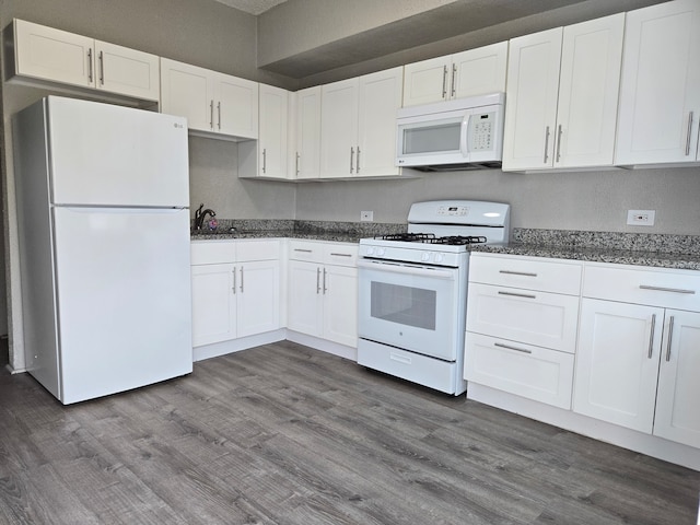 kitchen with dark hardwood / wood-style flooring, white cabinetry, dark stone counters, and white appliances