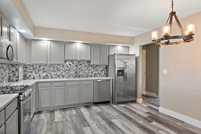 kitchen with gray cabinets, stainless steel appliances, sink, and light wood-type flooring