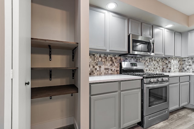 kitchen featuring light wood-type flooring, tasteful backsplash, gray cabinetry, and stainless steel appliances